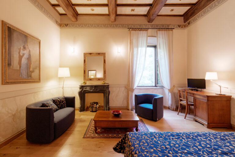 camera junior suite del castello di baccaresca con lounge camino decorativo e soffitto cassettone