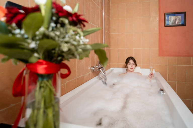 bagno della camera del castello di baccaresca con ospite nella vasca da bagno e vaso di fiori in primo piano
