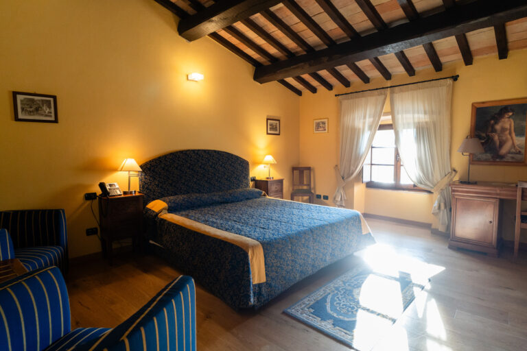 castello di baccaresca junior suite con travi a vista finestra luminosa e quadro romantico