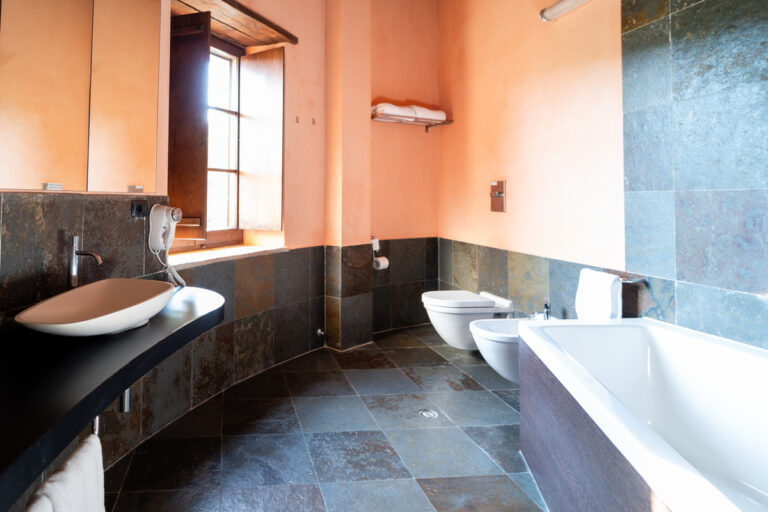 bagno della camera junior suite del castello di baccaresca con vasca da bagno e mattonelle scure in contrasto con muri accesi