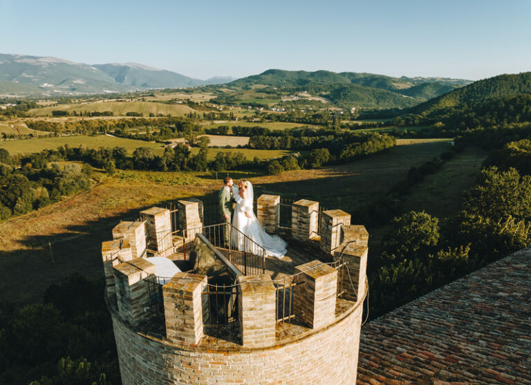 Coppia di sposi che si guarda negli occhi in cima alla torre del castello con vista panoramica sulla tenuta verdeggiante