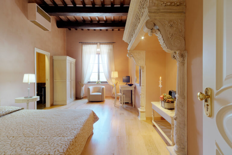 camera junior suite del castello di baccaresca con finestra luminosa e camino monumentale