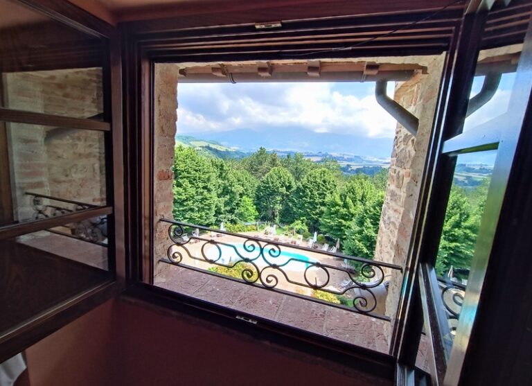 Scorcio panoramico da una delle finestre della suite. Piscina a vista con alberi e montagne nello sfondo