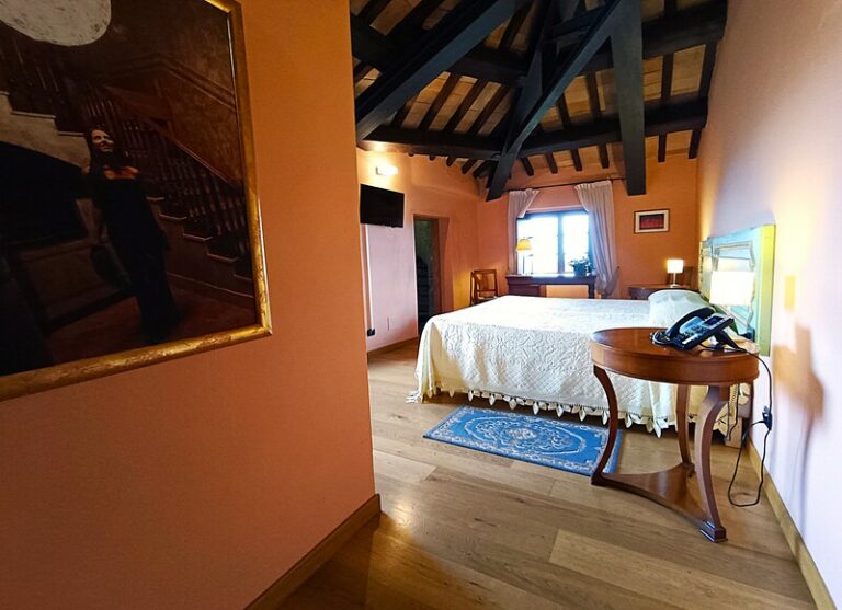 Ingresso Tower suite con quadro alla parete telefono e televisione in bella vista e letto sullo sfondo. Travi del soffitto a vista