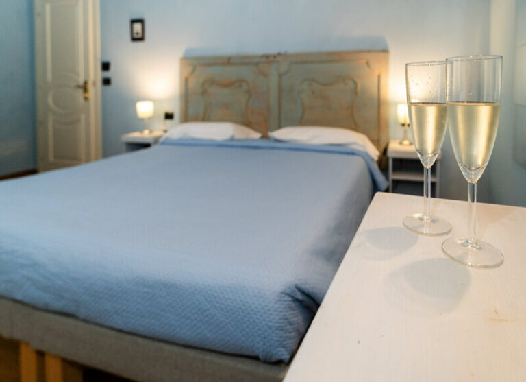 Camera classic del castello di baccaresca con calici di benvenuto in primo piano e letto matrimoniale sullo sfondo