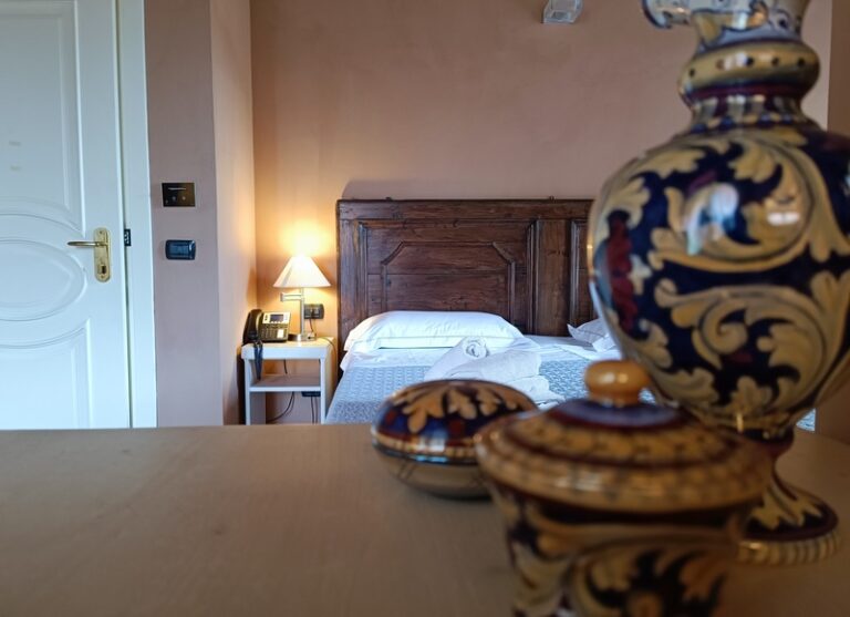 Deluxe camera con ceramiche in primo piano e letto matrimoniale in secondo piano con entrata a sinistra