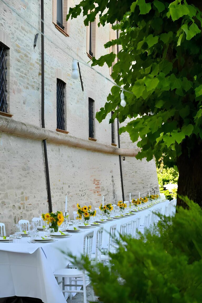 outdoor venue with long white table and sunflowers as decoration. private event in the castle of gubbio