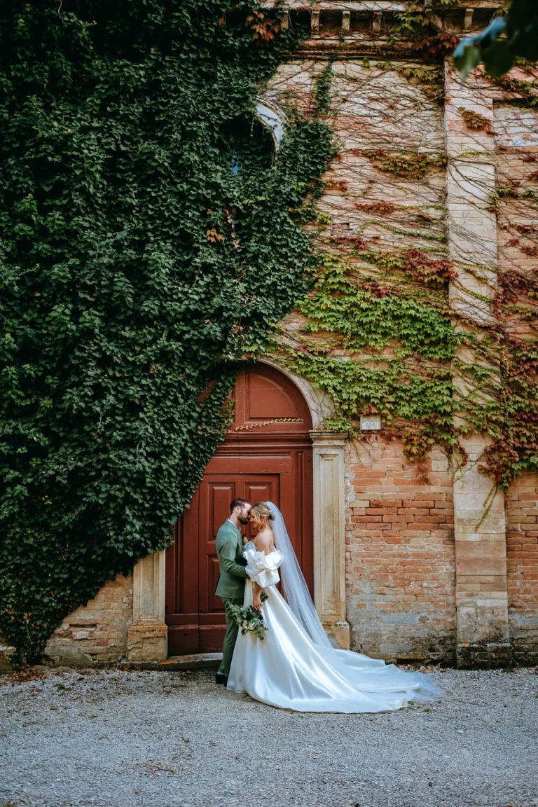 Sposi in posa davanti al portone antico della Chiesa di S.Anna parte della tenuta del Castello di Baccaresca, storica location per matrimoni a Gubbio in Umbria