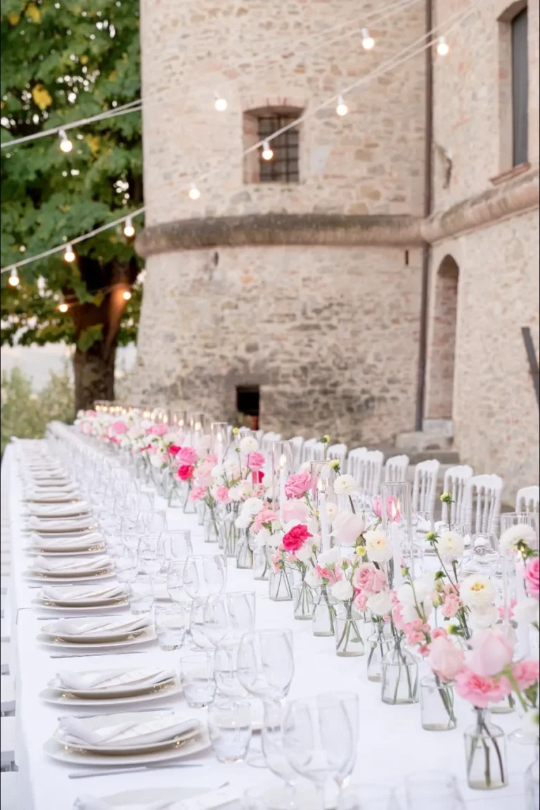 Tavolo imperiale da matrimonio all'aperto ai piedi della torre del Castello di Baccaresca, allestito con fiori rosa e bianchi