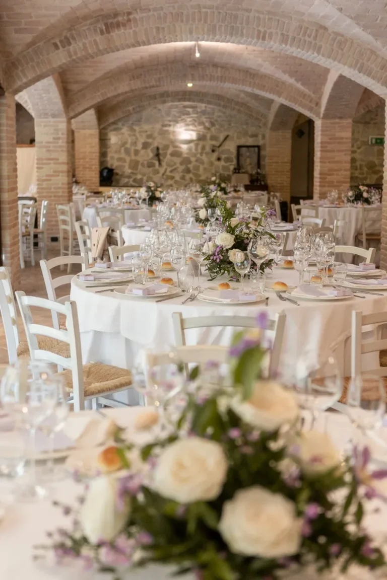 Sala interna del ristorante del Castello di Baccaresca con soffitto a volte in mattoni e tavoli rotondi apparecchiati.